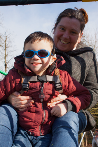 Child sitting on adult's knee in park