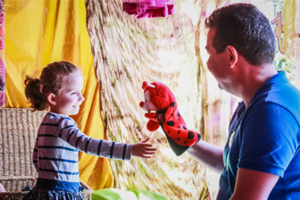 Child playing with puppet and adult