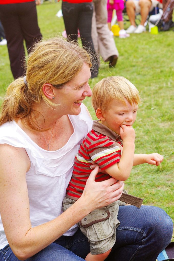 Parent holding child in arms at an outdoor event