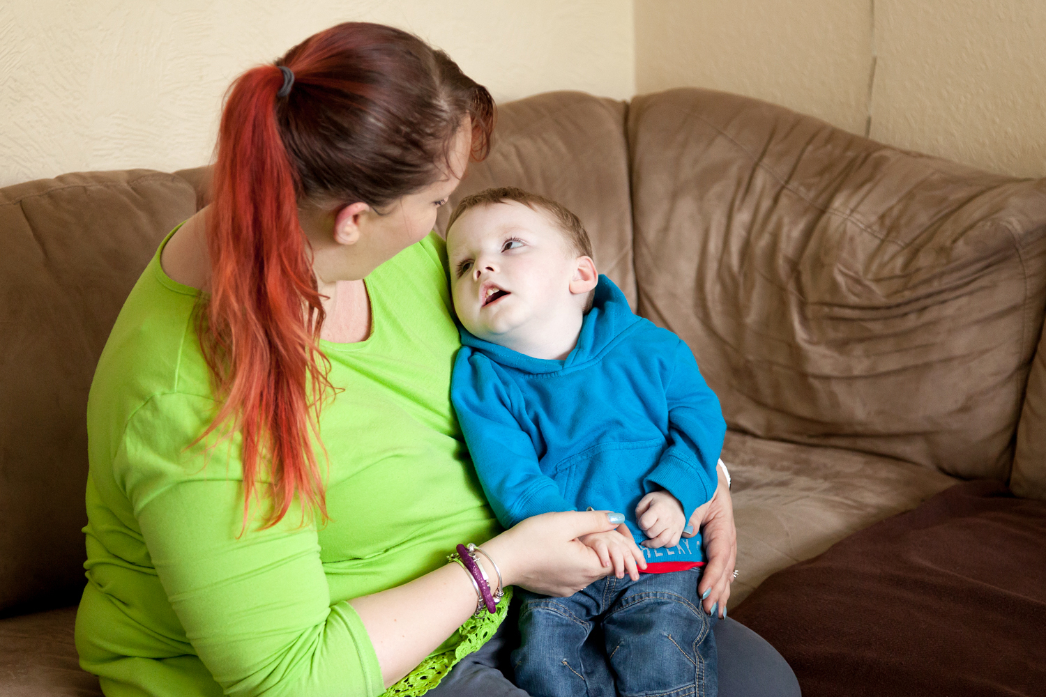 Woman in green jumper on sofa with child sitting on her lap