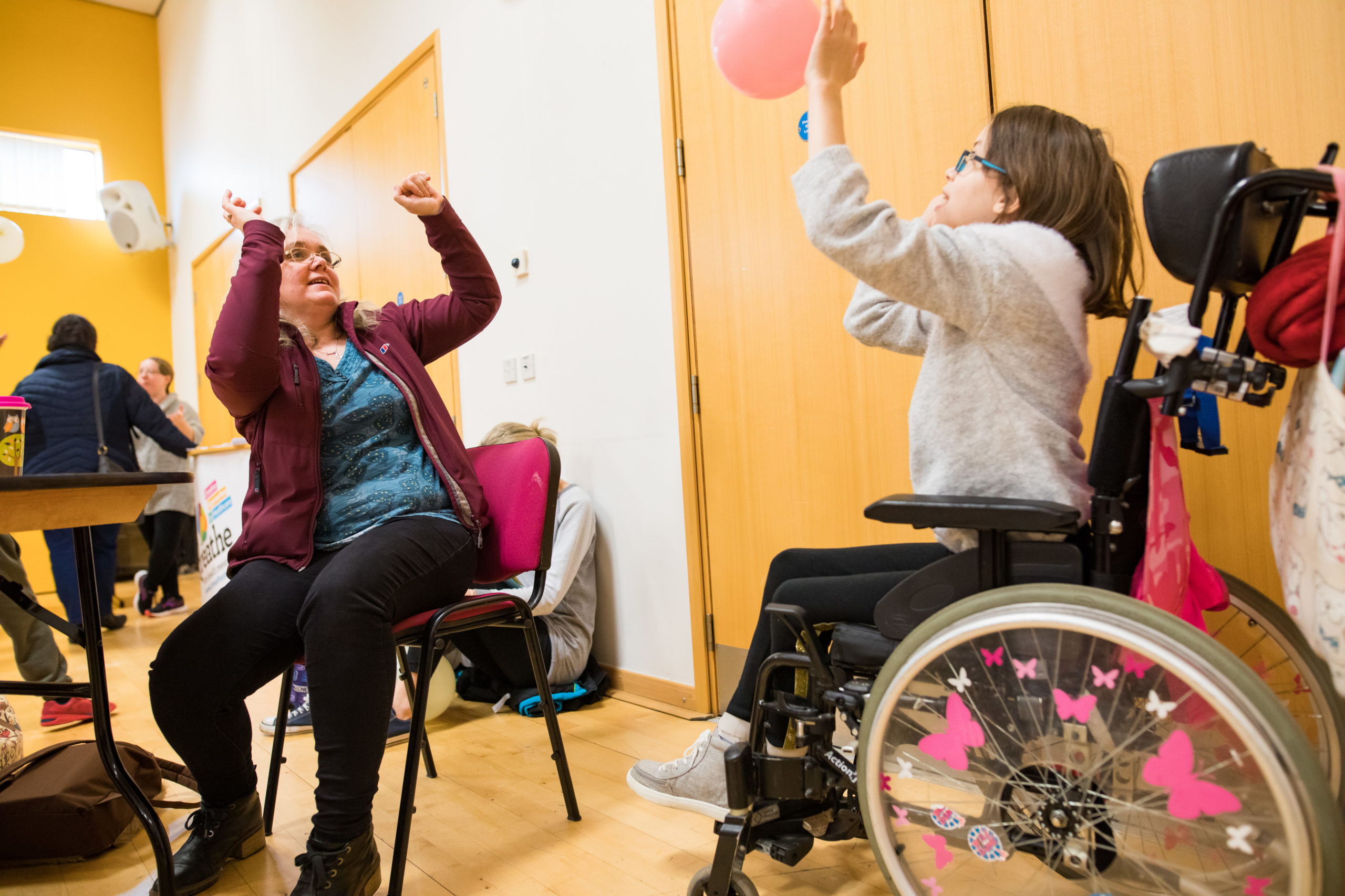 HemiHelp event - child in wheelchair playing balloon game with adult