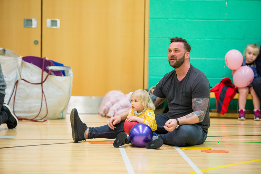 HemiHelp event - father sitting on floor with child, who is holding a ball
