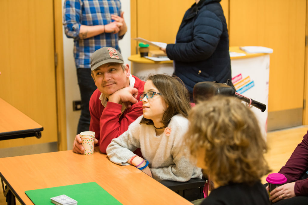 HemiHelp event - child and adult sitting at table, adult has cup in hand