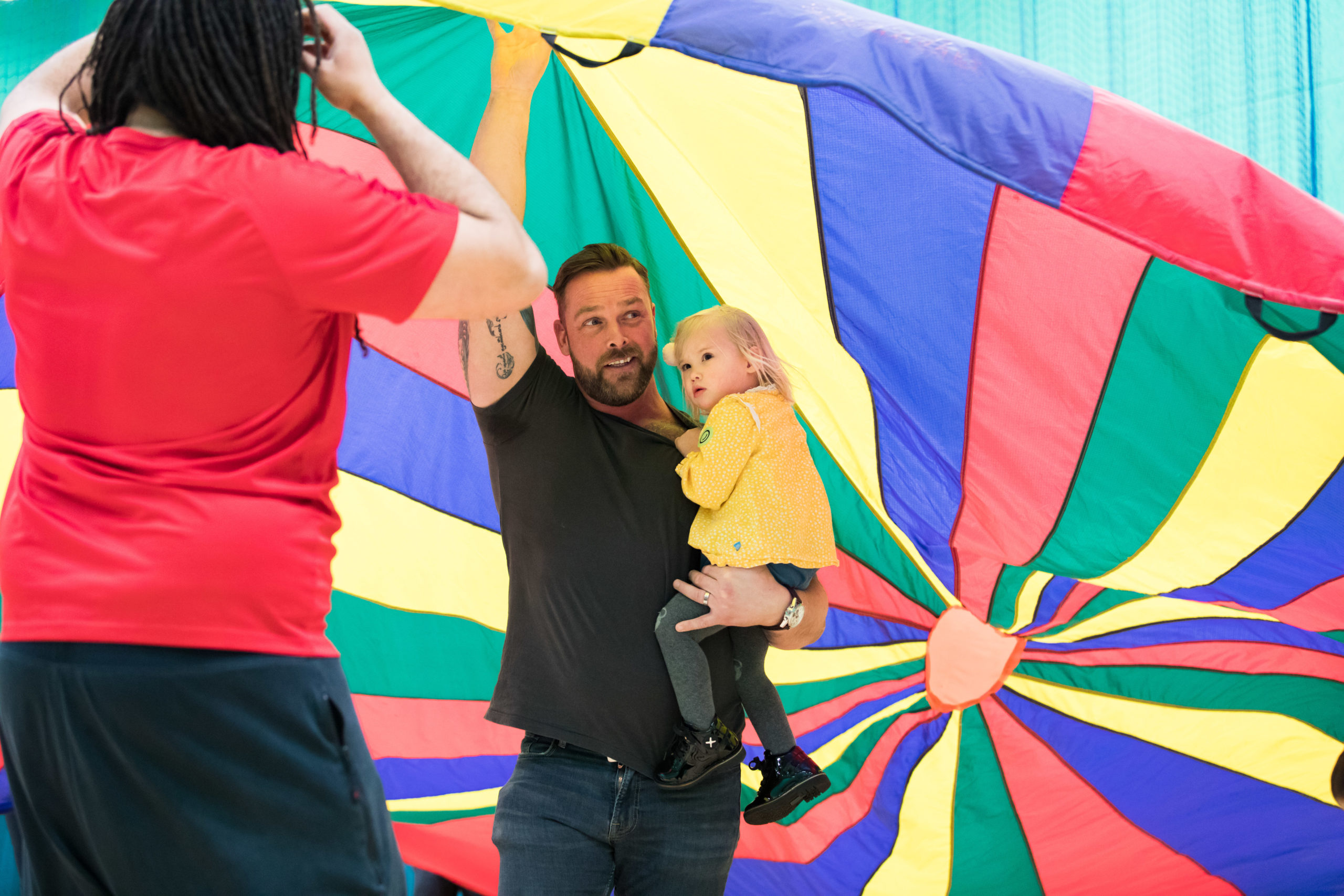 HemiHelp event - adult and child standing under colourful parachute play tent