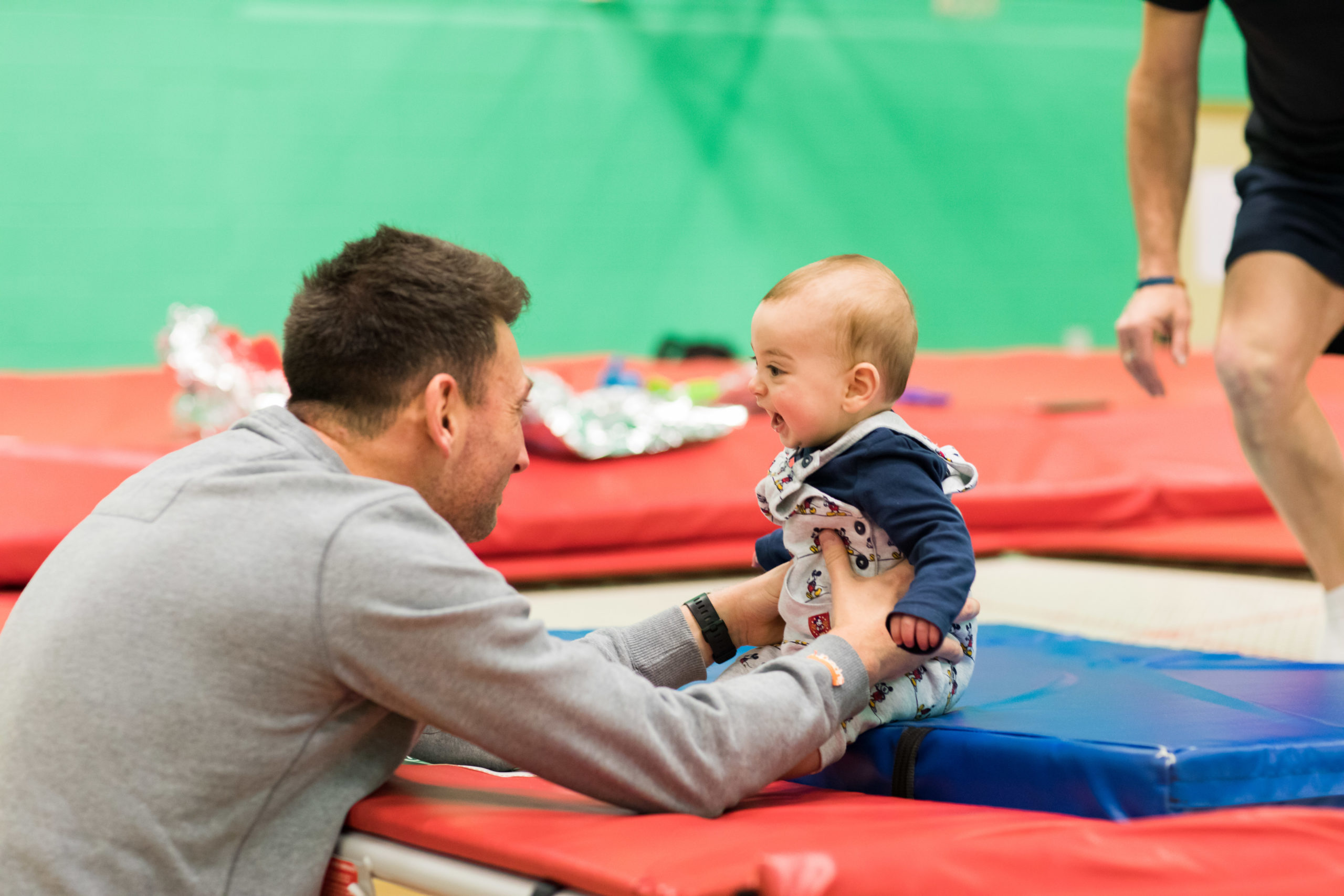 HemiHelp event - adult holding baby, baby is sitting on trampoline