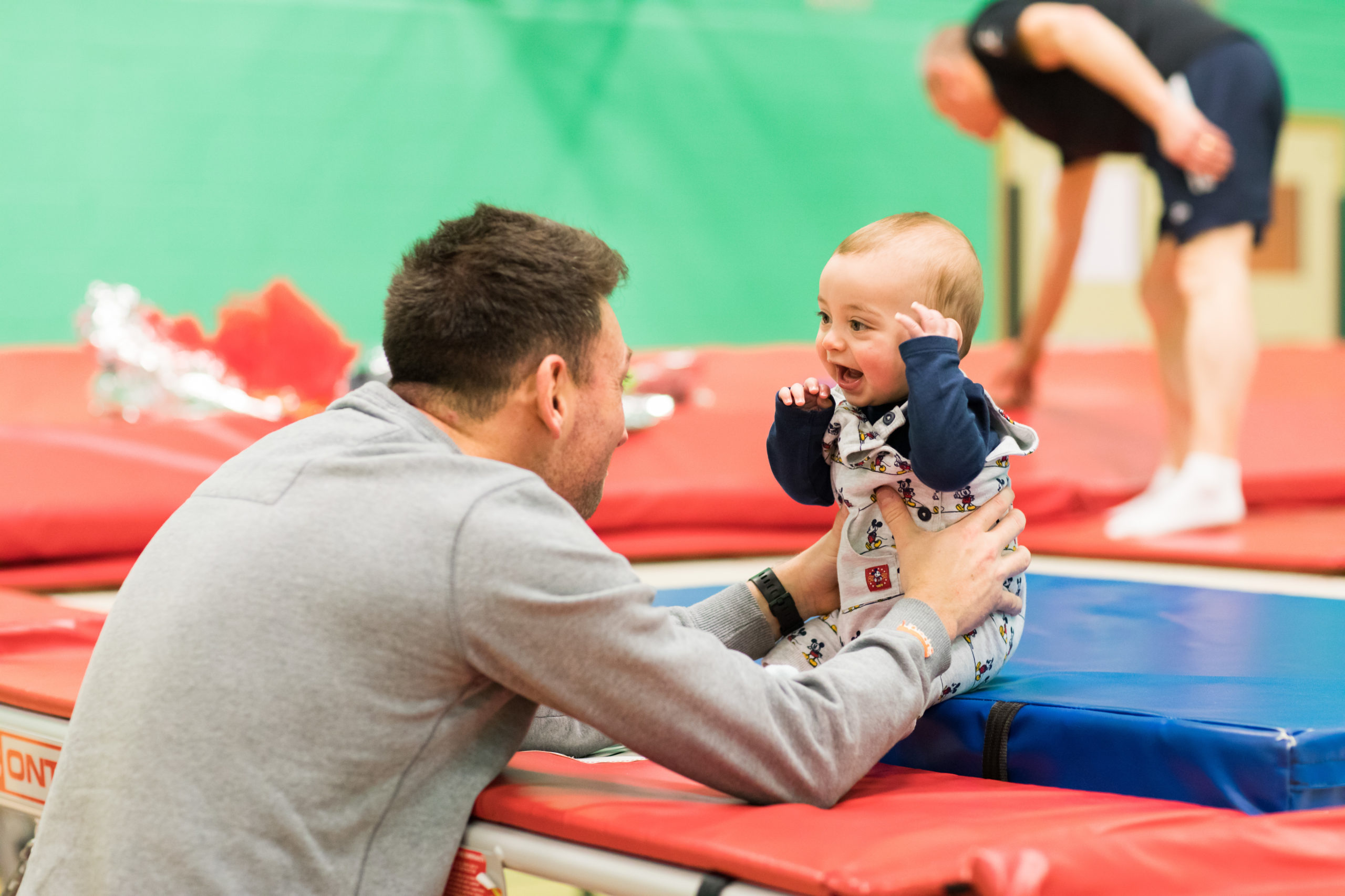 HemiHelp event - adult holding baby, baby is sitting on trampoline