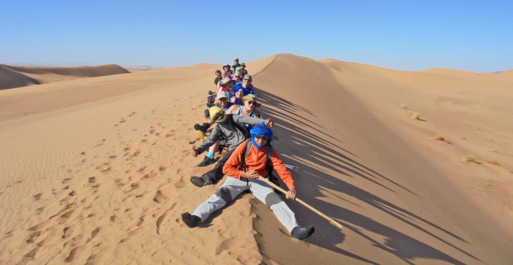Group of people sitting on a dune in the Sahara Desert