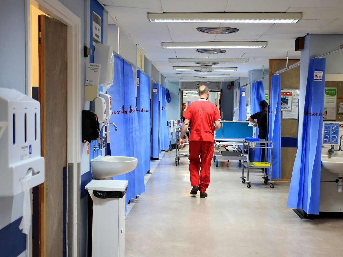 Medical staff walking through hospital ward away from camera