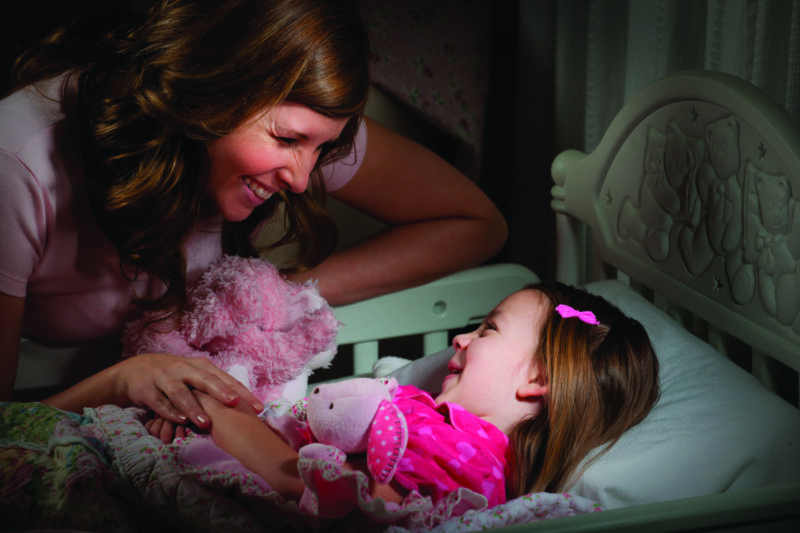 Mum smiling at small daughter with toys at bedtime