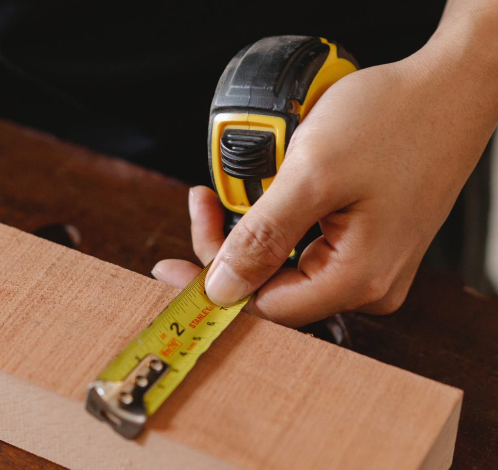Hand holding tape measure against wood