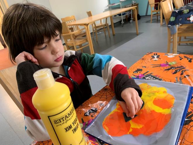 A child finger painting at a desk
