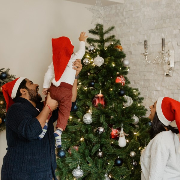 Parents lifting child to top of Christmas tree