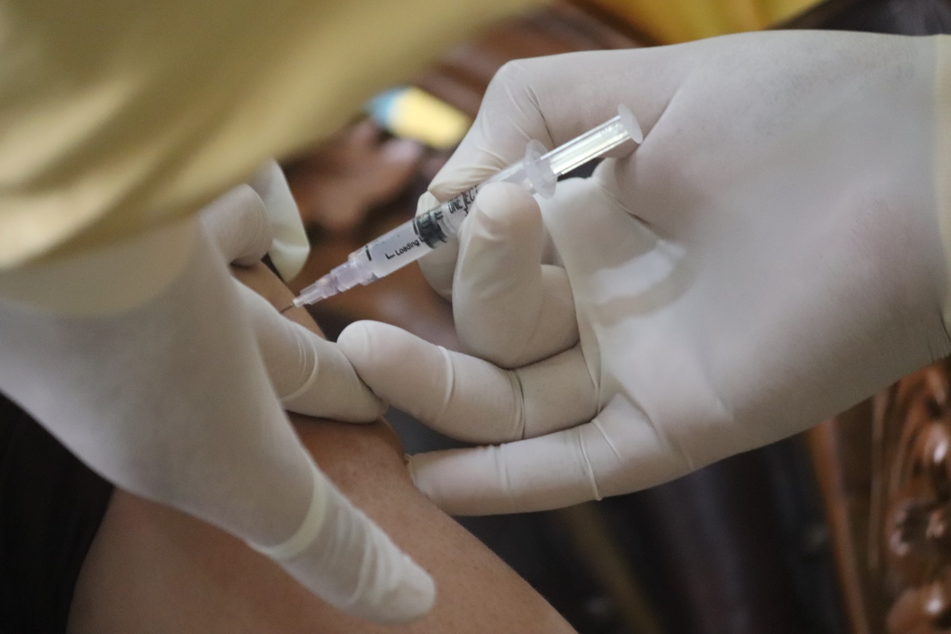 The hands of a medical professional giving someone a vaccine shot
