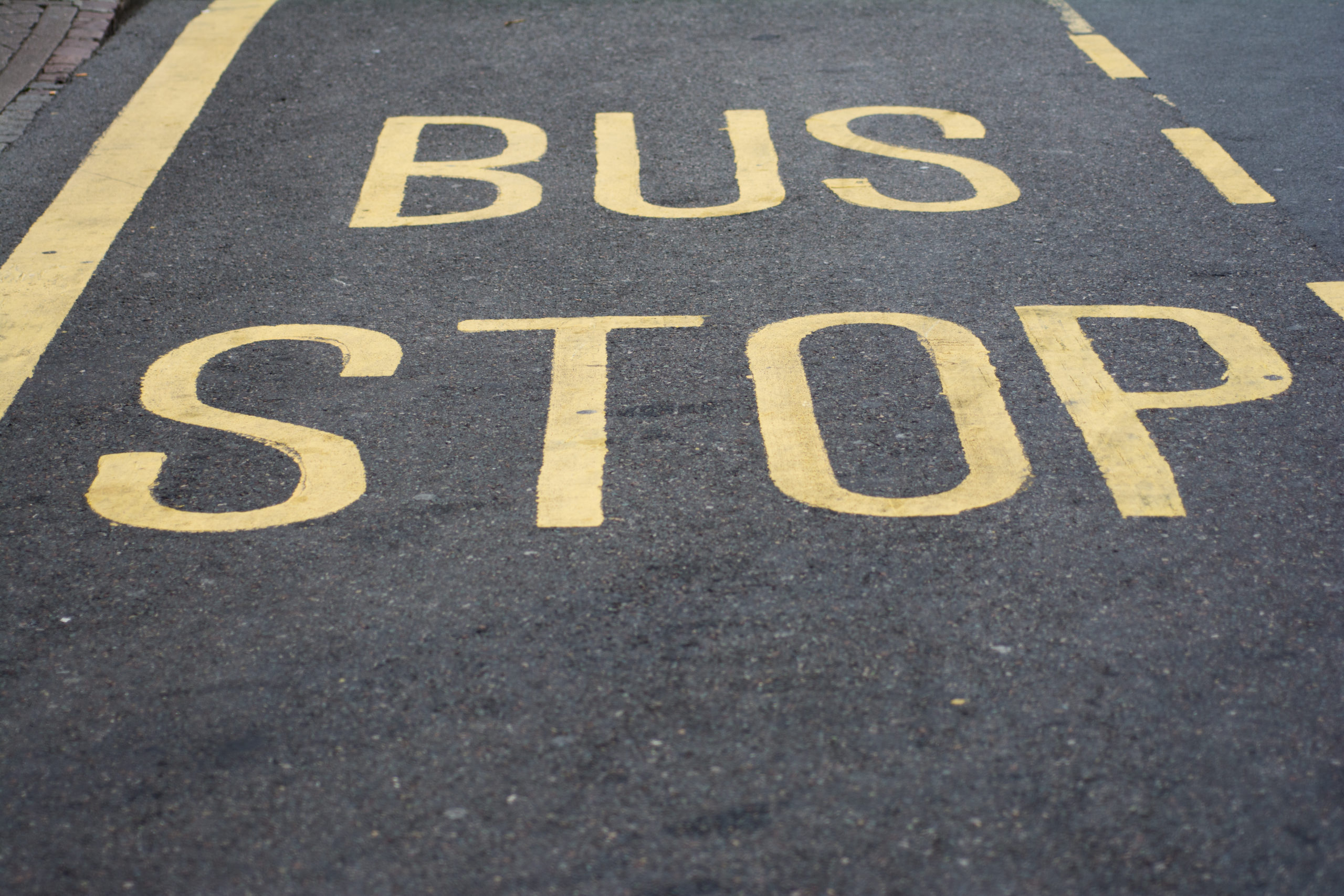 UK bus stop sign on tarmac road