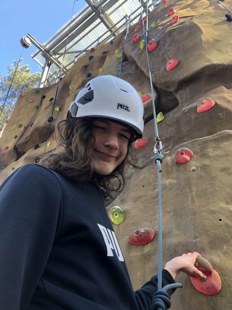 Teenager wearing helmet at rock climbing wall