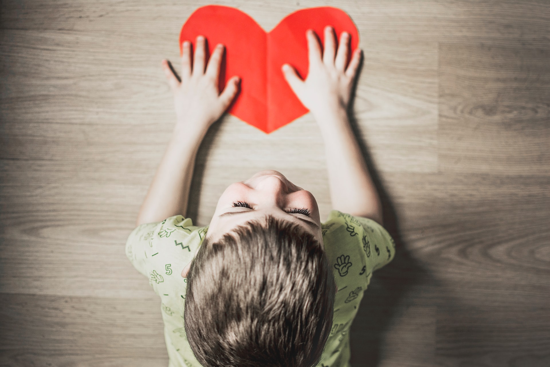 Young child holding a red heart made out of paper