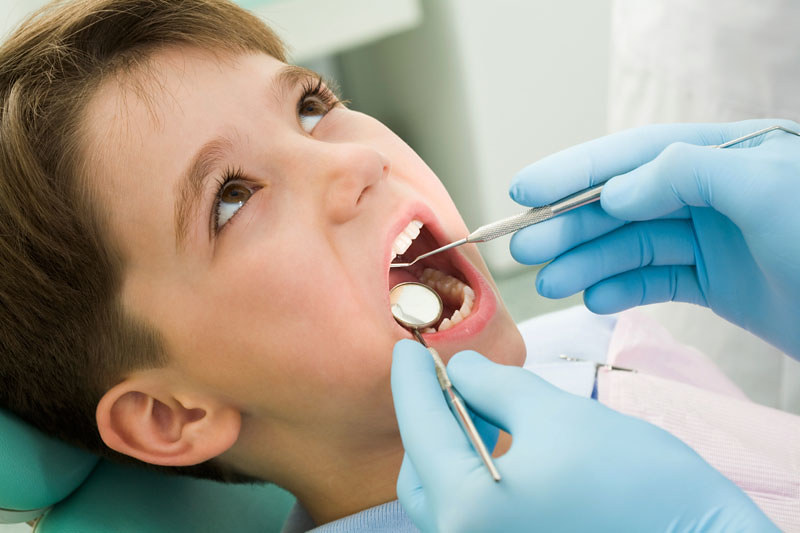 Young boy having his mouth examined at the dentist