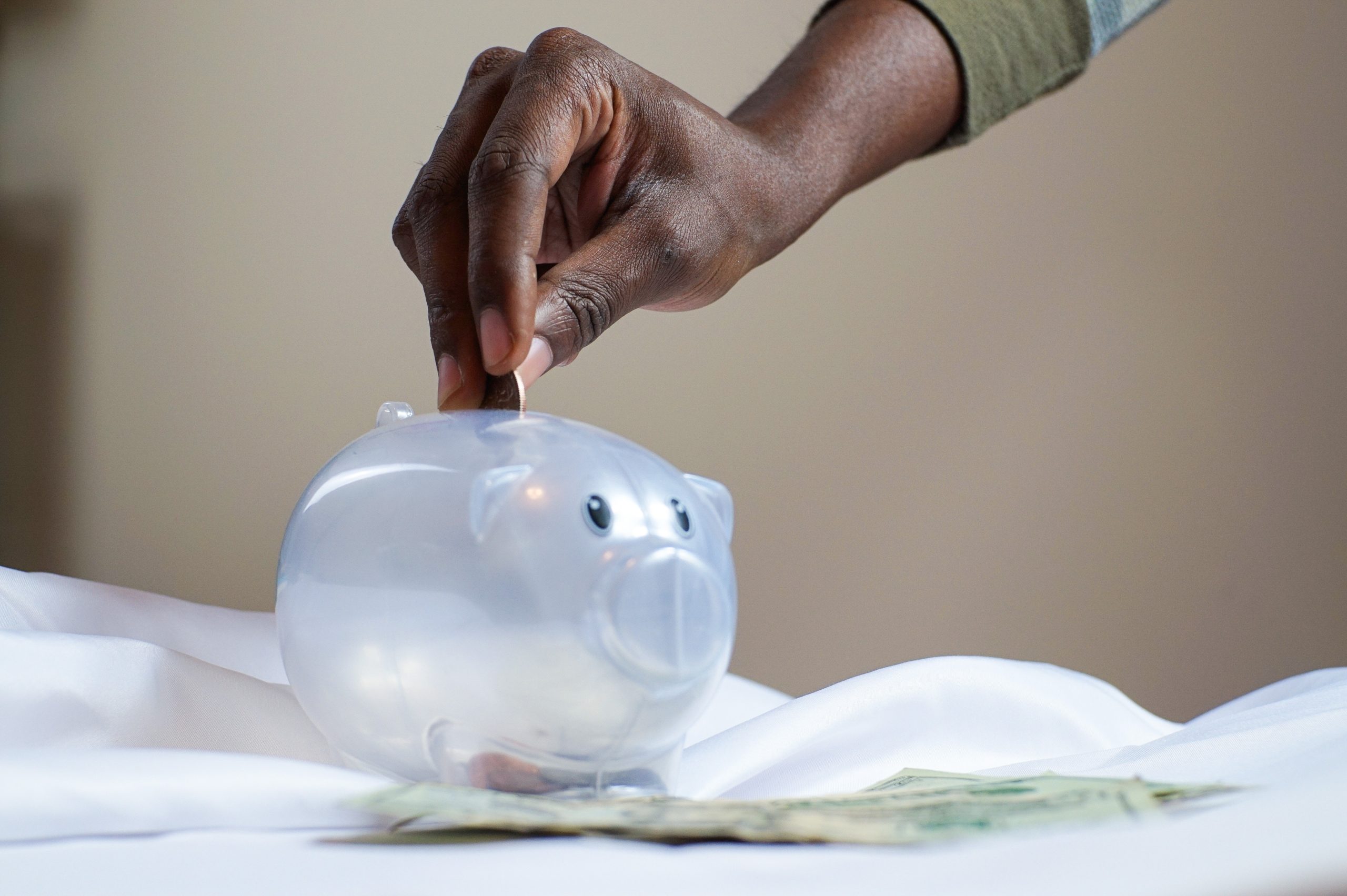 Hand putting money into a piggy bank