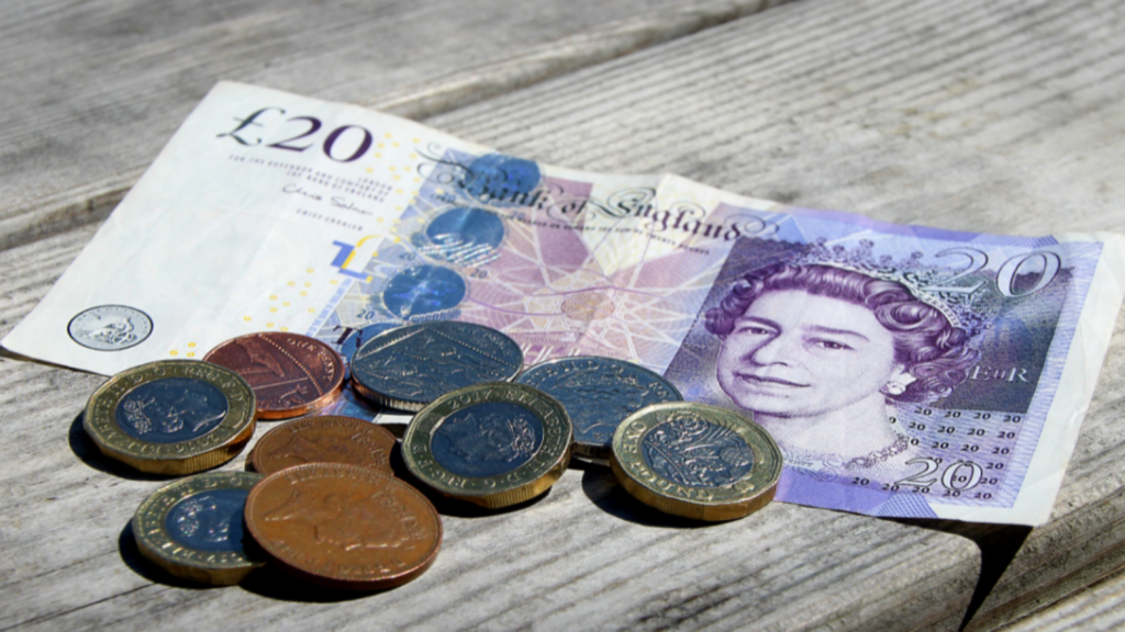 £20 bank note and coins on a table