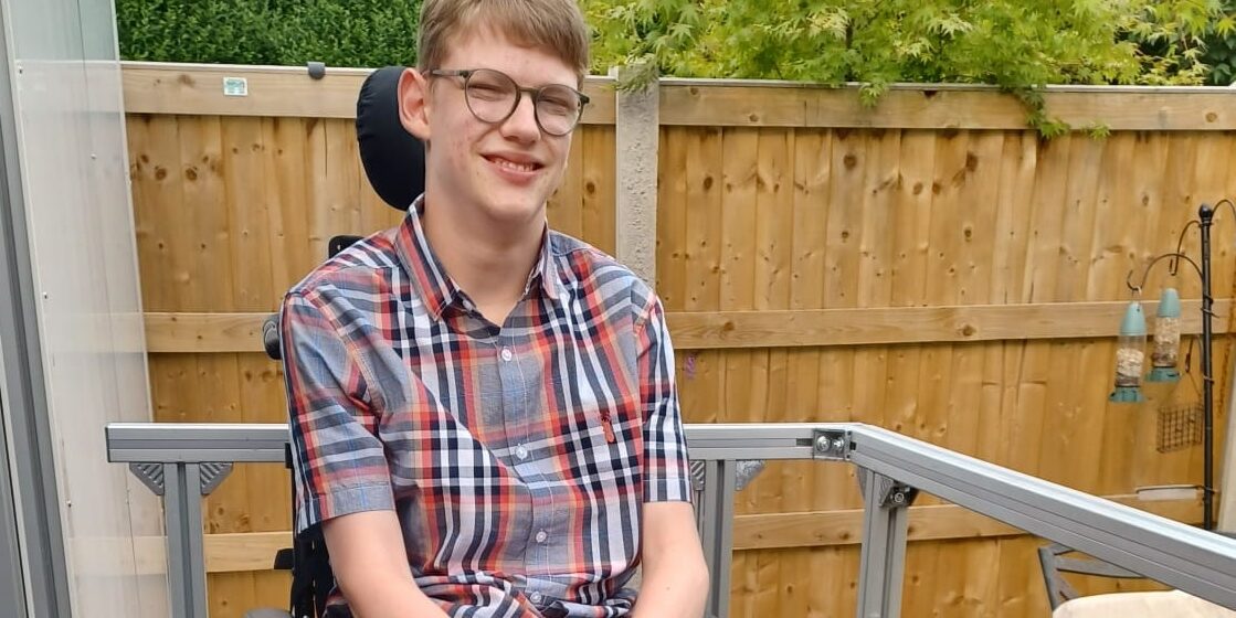 Young man in wheelchair sat outside house
