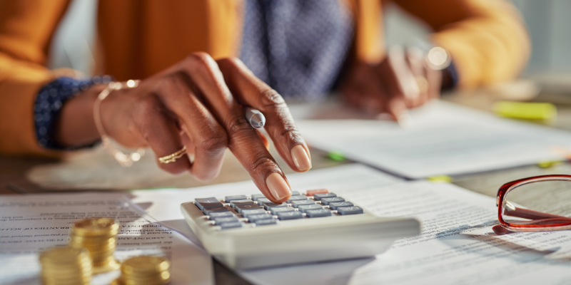 Close up of woman's hand typing into a calculator on an office desk