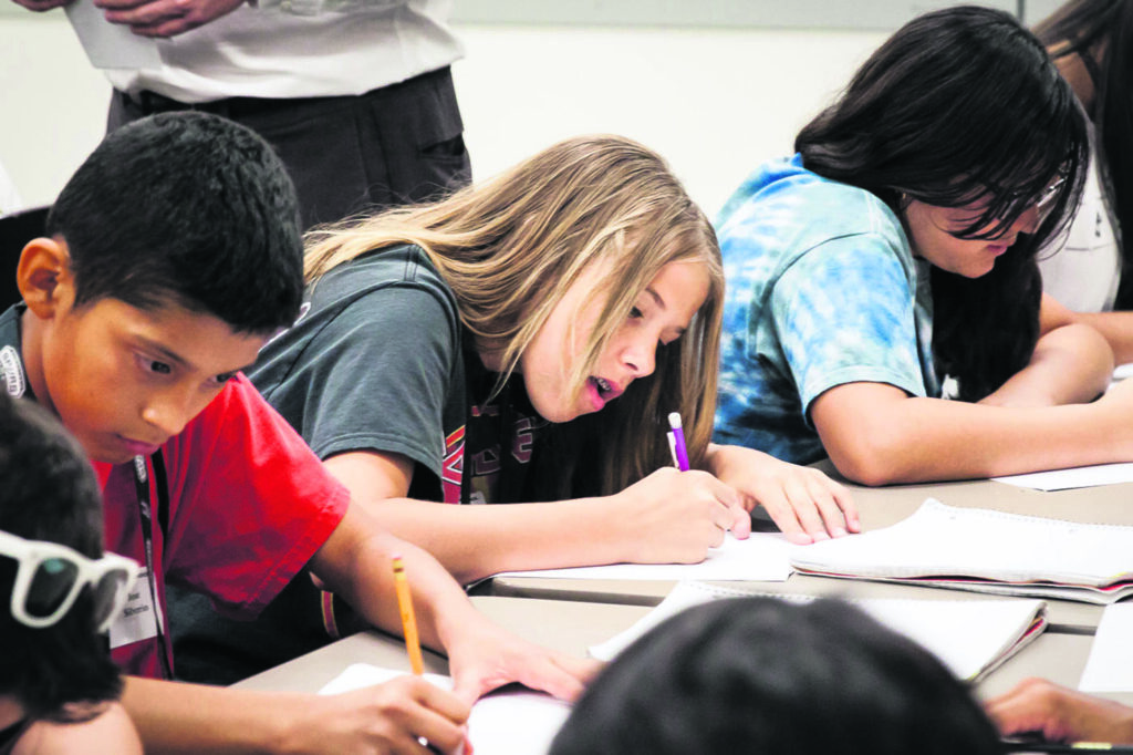 Children at a school desk writing on paper