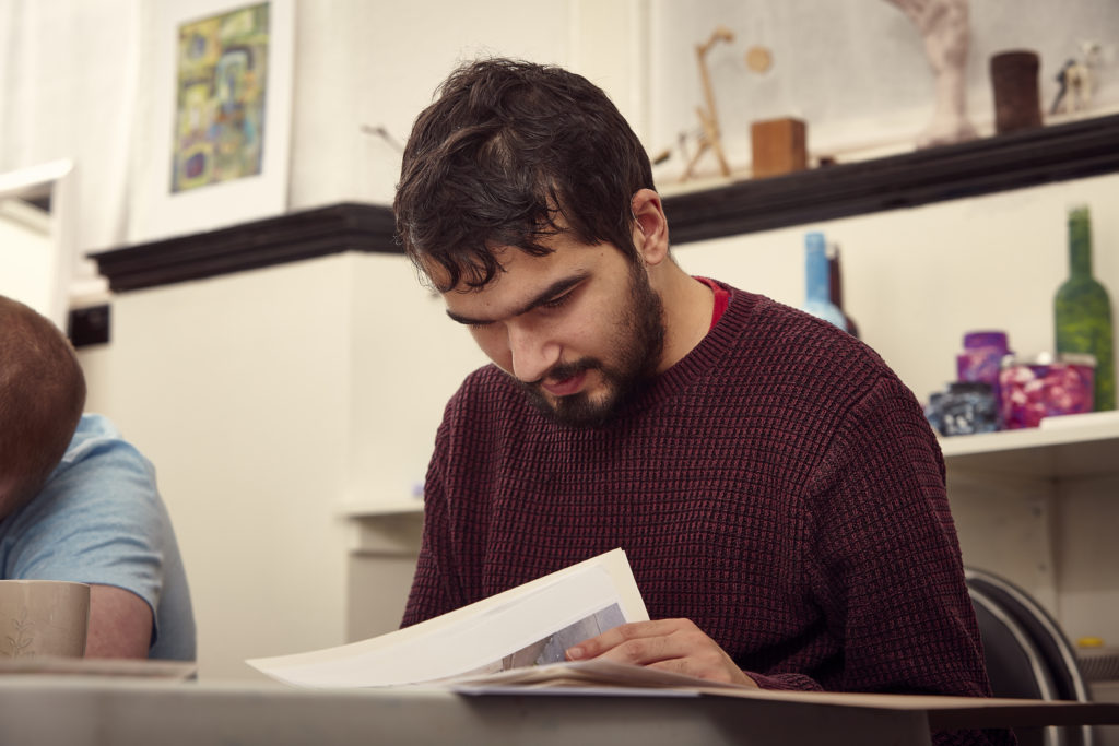 A man studying a piece of paper at a desk.
