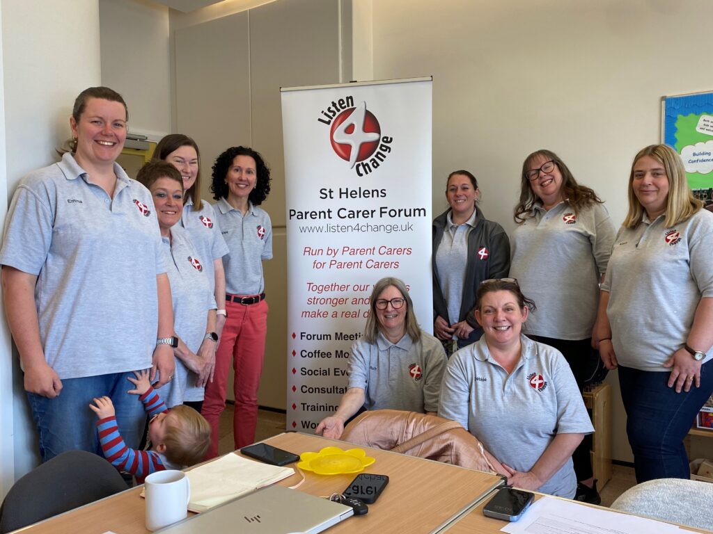 9 members of the St Helens parent carer forum standing in front of their banner.