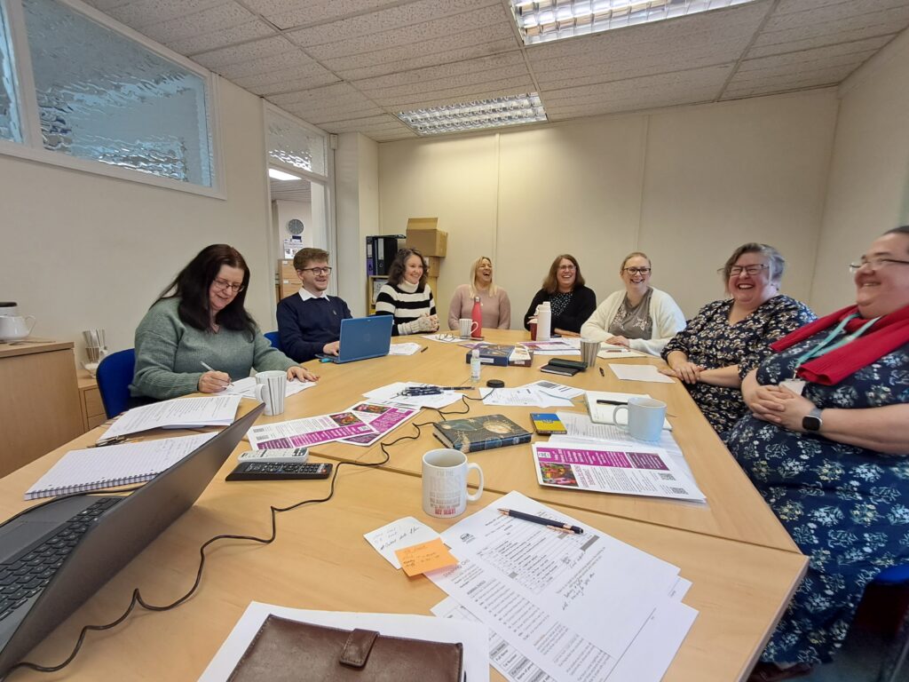 eight members of a parent carer forum sitting around a desk having a meeting.