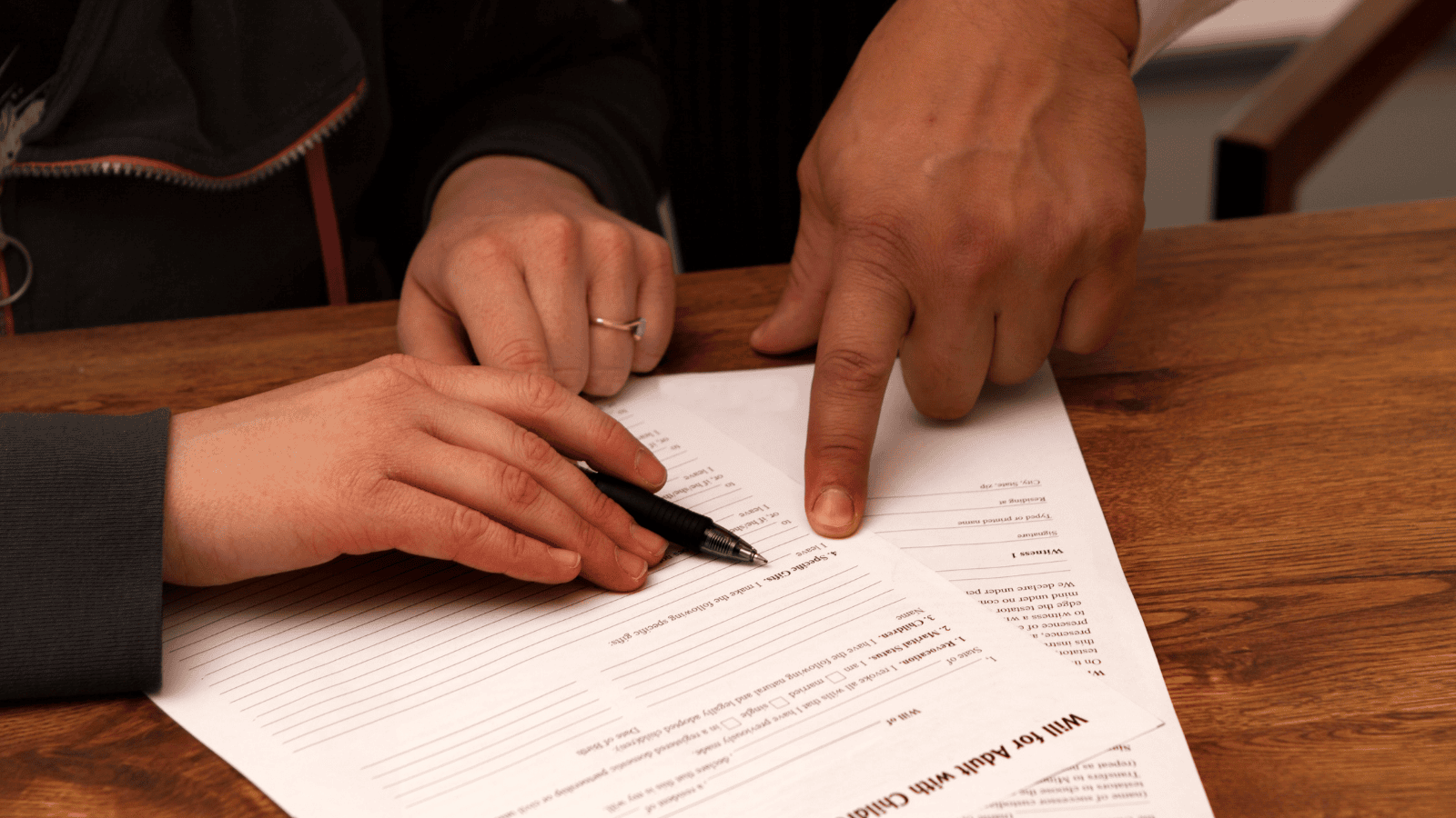Close up of two adult hands signing a Will document