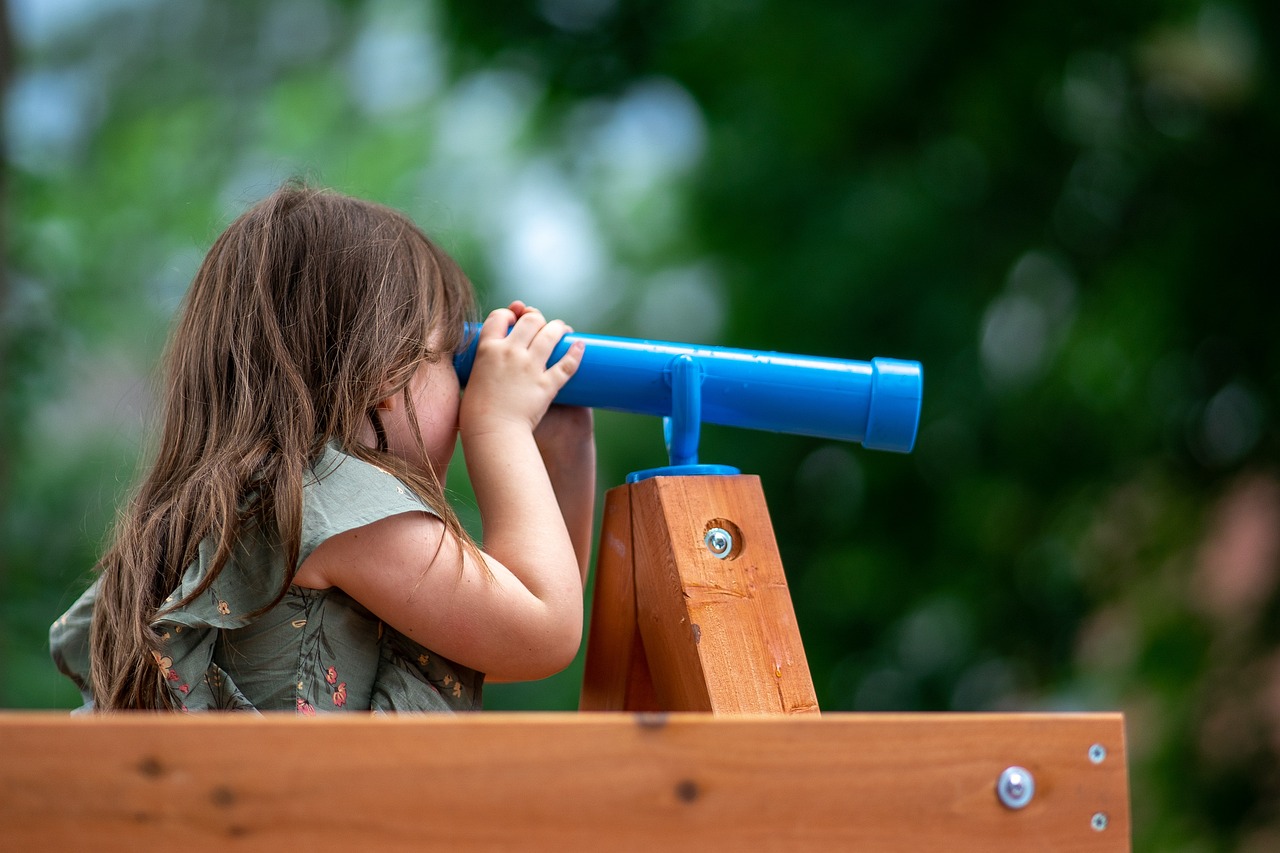 Child looking through a telescope on a wooden structure
