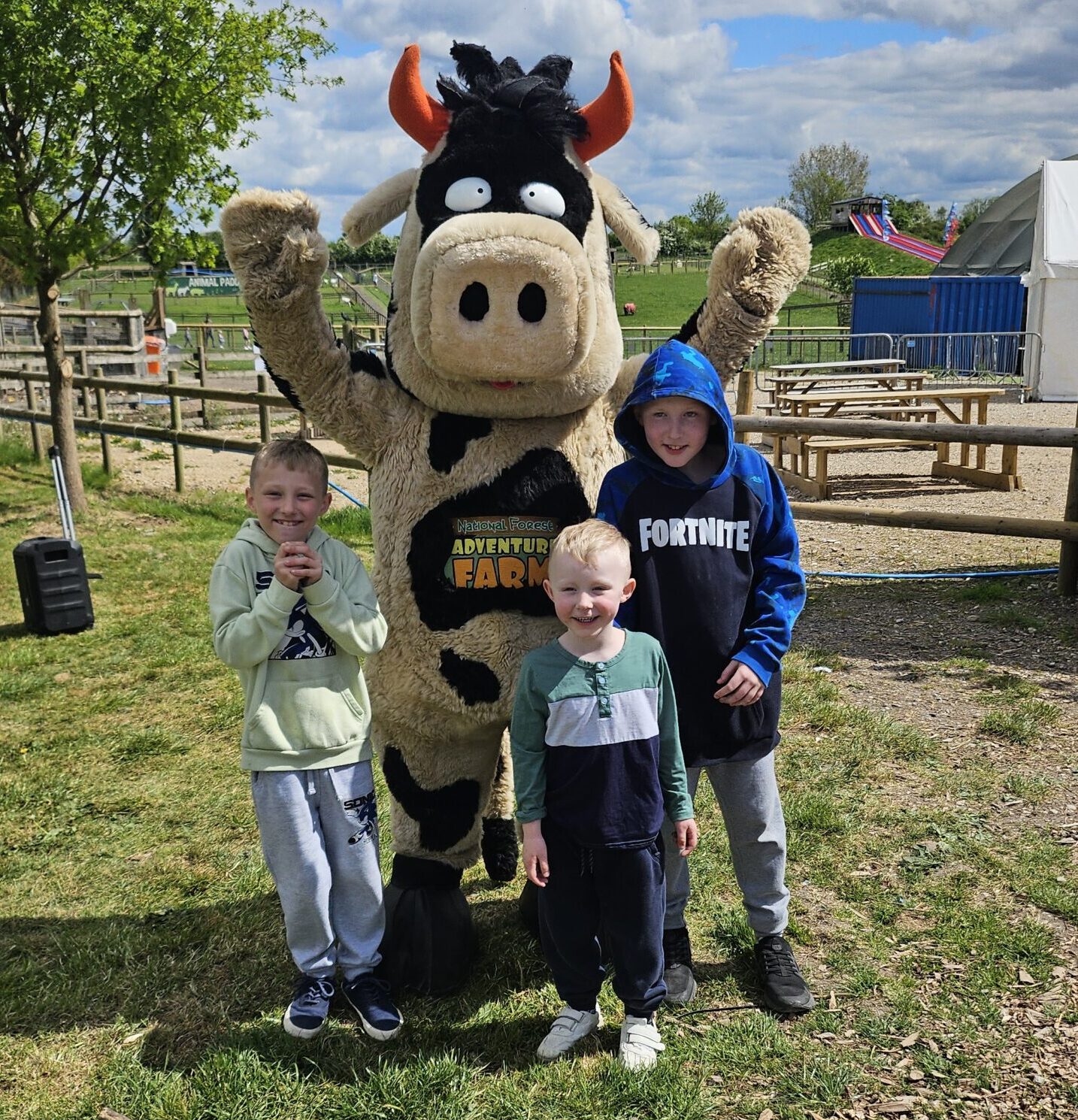 Three young boys smiling next to farm mascot