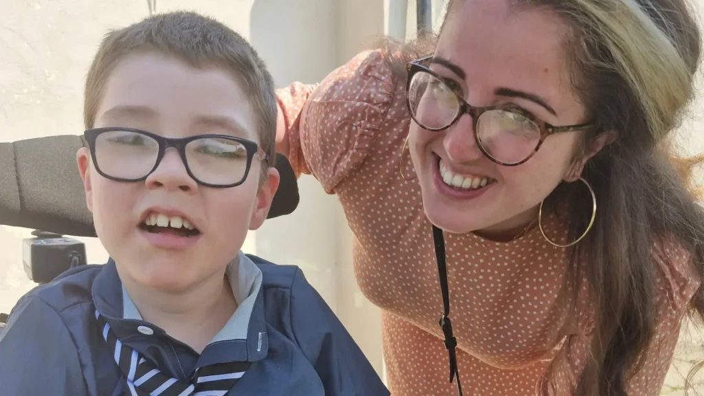 A young boy and his mum smiling into the camera.