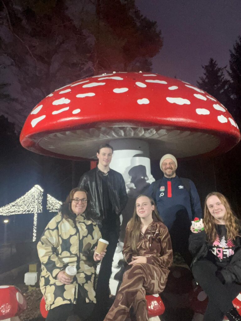 A family standing under a giant mushroom attraction.