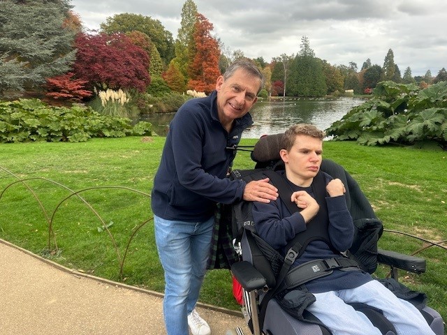 A father walking his teenage son in a wheelchair