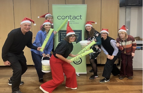 Contact colleagues dressed in Santa hats in front of a Contact banner.