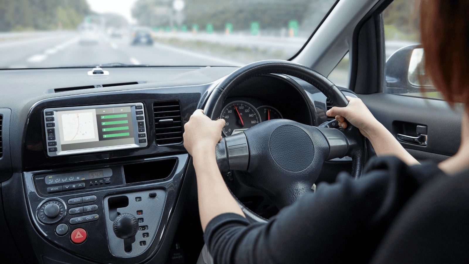 Person holding a car steering wheel