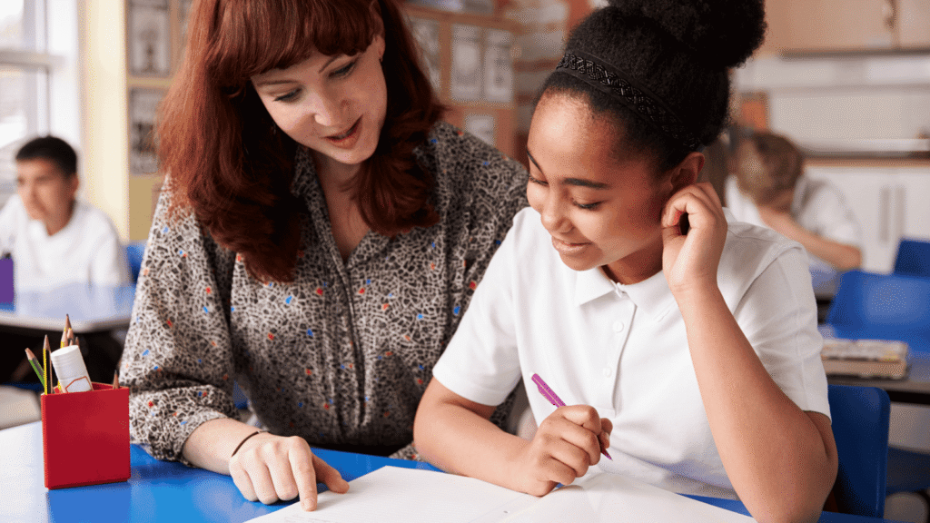 A teacher reading with a pupil