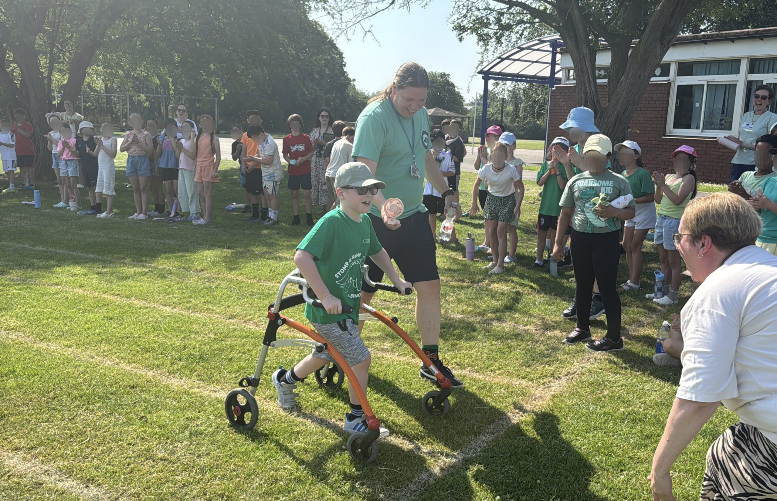 Boy completing DinoDay fundraising challenge walk cheered on by classmates