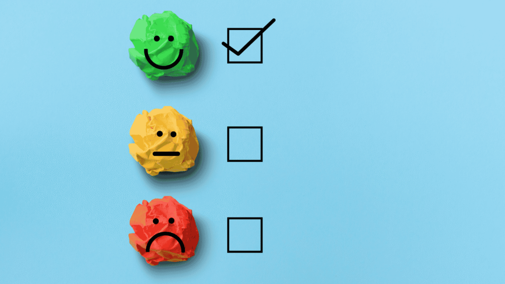 Three crumpled papers—green with a happy face, yellow with a neutral face, and red with a sad face—are next to tickboxes.